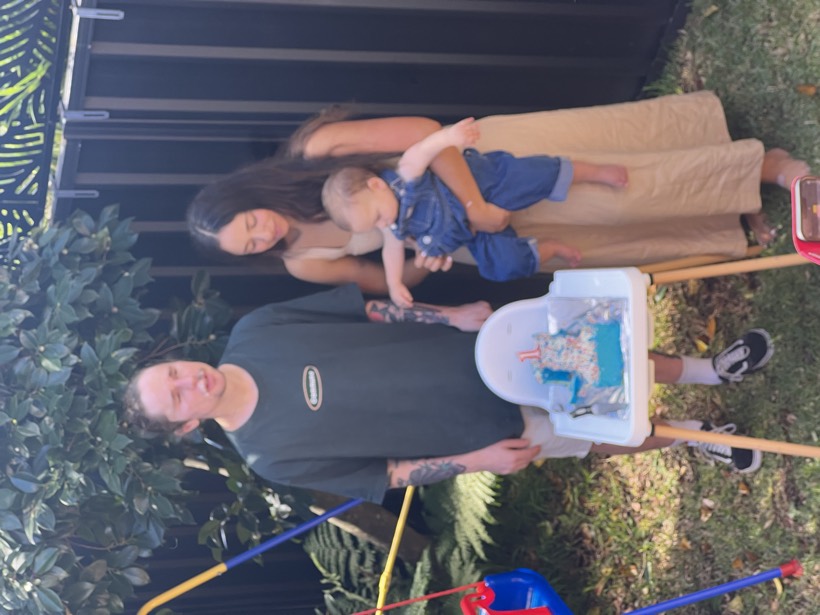 Brittany and Deklan gathered outside with a child and birthday cake.