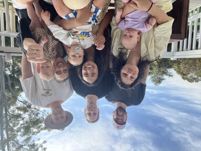 Friends and family gathered outside with babies, smiling together.