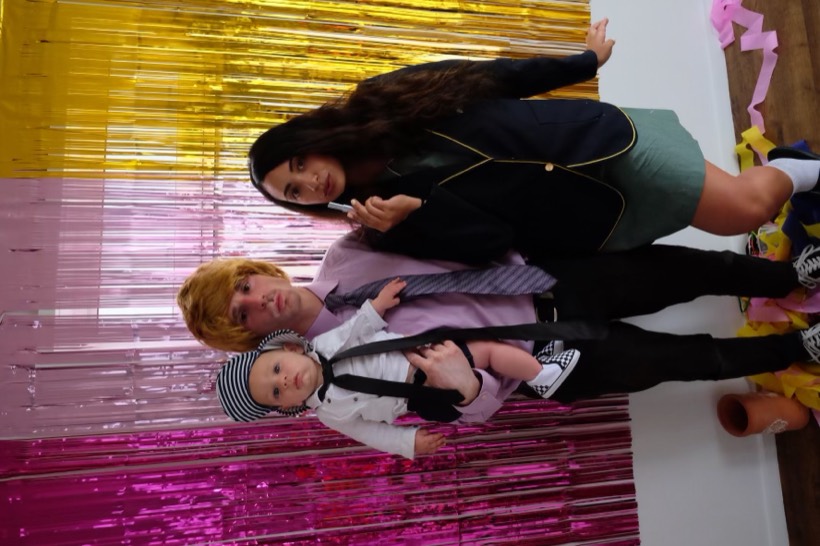 A playful costume photo with loved ones in front of shiny streamers.
