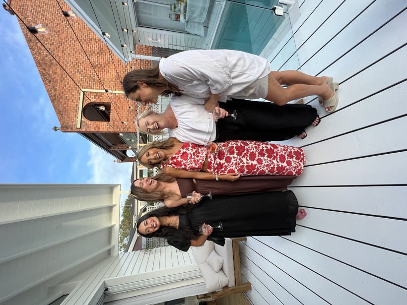 A group of women laughing together near a pool.