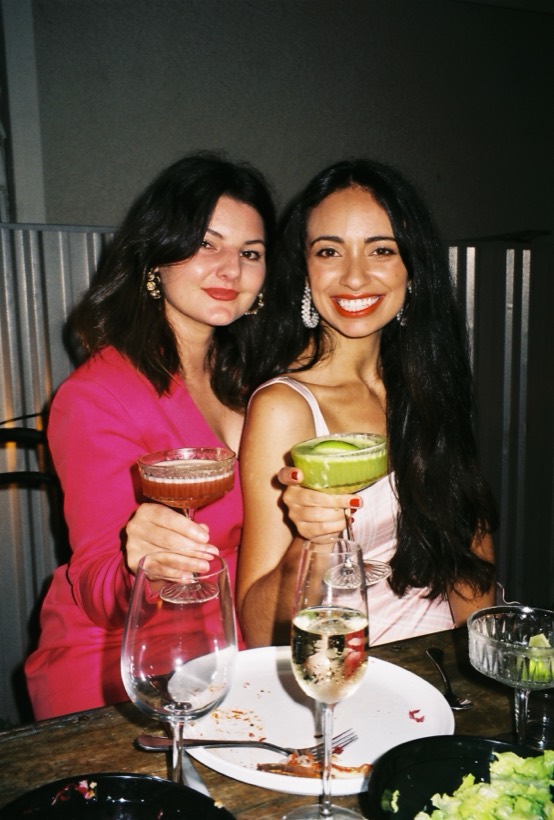 Brittany and a friend smiling with colorful drinks.