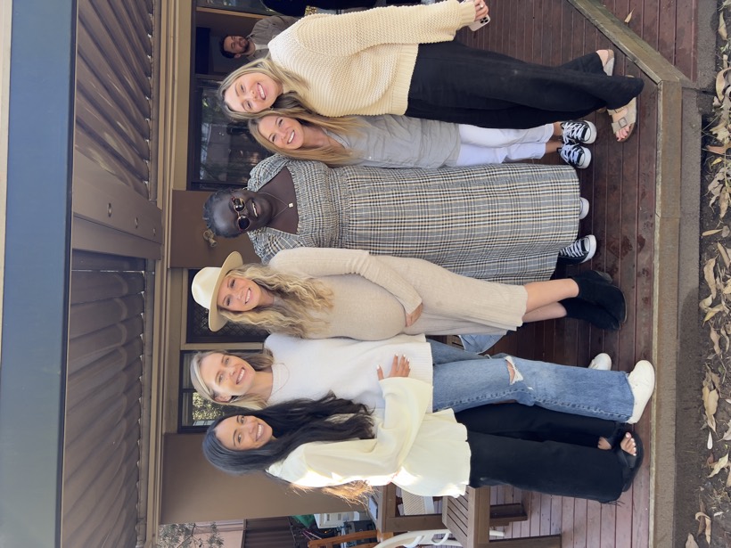 A group of women gathered closely together and smiling.
